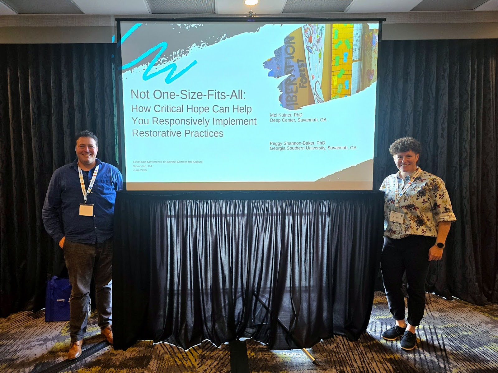 Facilitators Mel Kutner and Peggy Shannon-Baker stand with their presentation screen showing their title "Not One-Size-Fits-All: How Critical Hope Can Help You Responsively Implement Restorative Practices"
